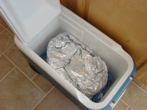 Foiled briskets resting in an empty cooler