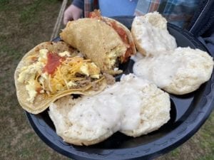 Plate of brisket and sausage breakfast tacos with biscuits and gravy