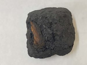 Small piece of unburned wood in Kingsford Original 1984 briquet
