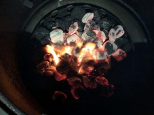 Lit charcoal spread over wood chunks and unlit charcoal