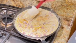 Stirring shredded cheddar cheese into corn mixture