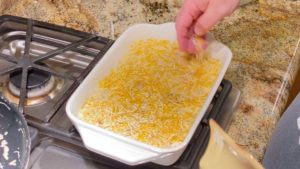 Topping cheesy corn with more shredded cheese