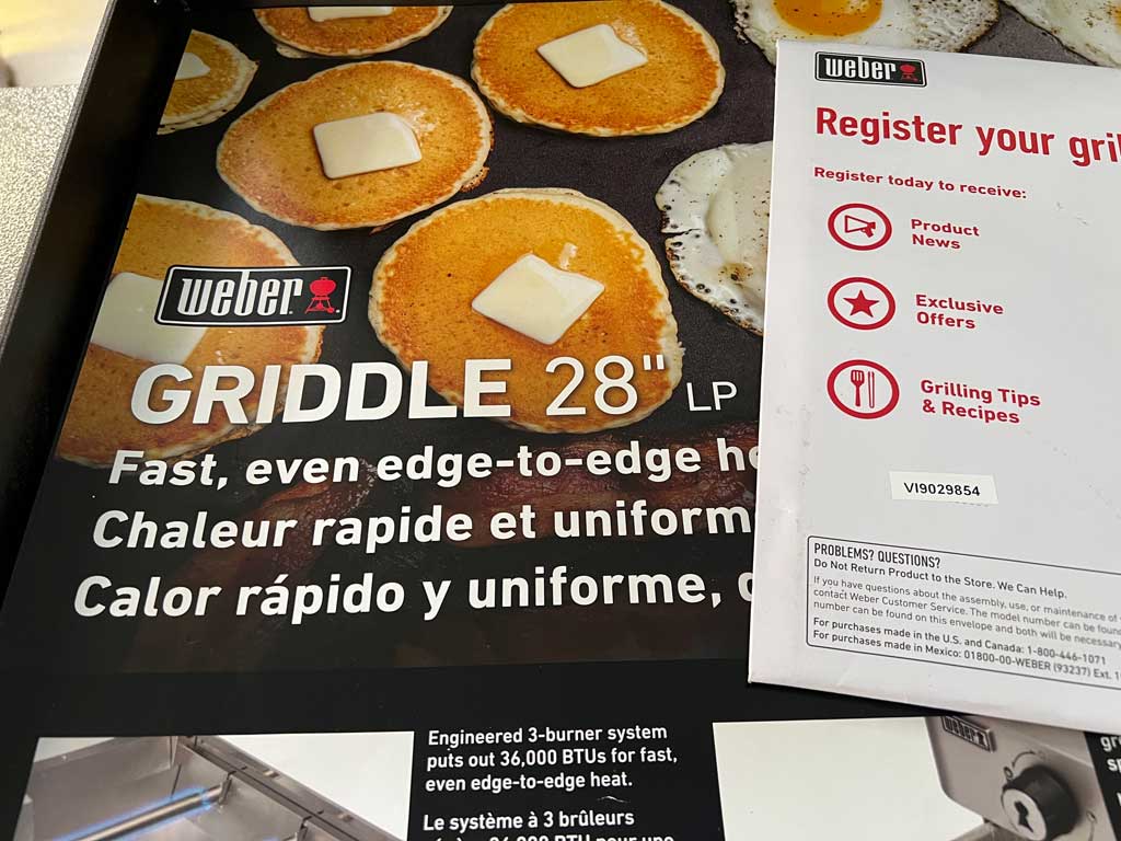 Example of 2023 VI serial number on a Weber Griddle owner's manual on top of a retail point-of-sale advertisement.